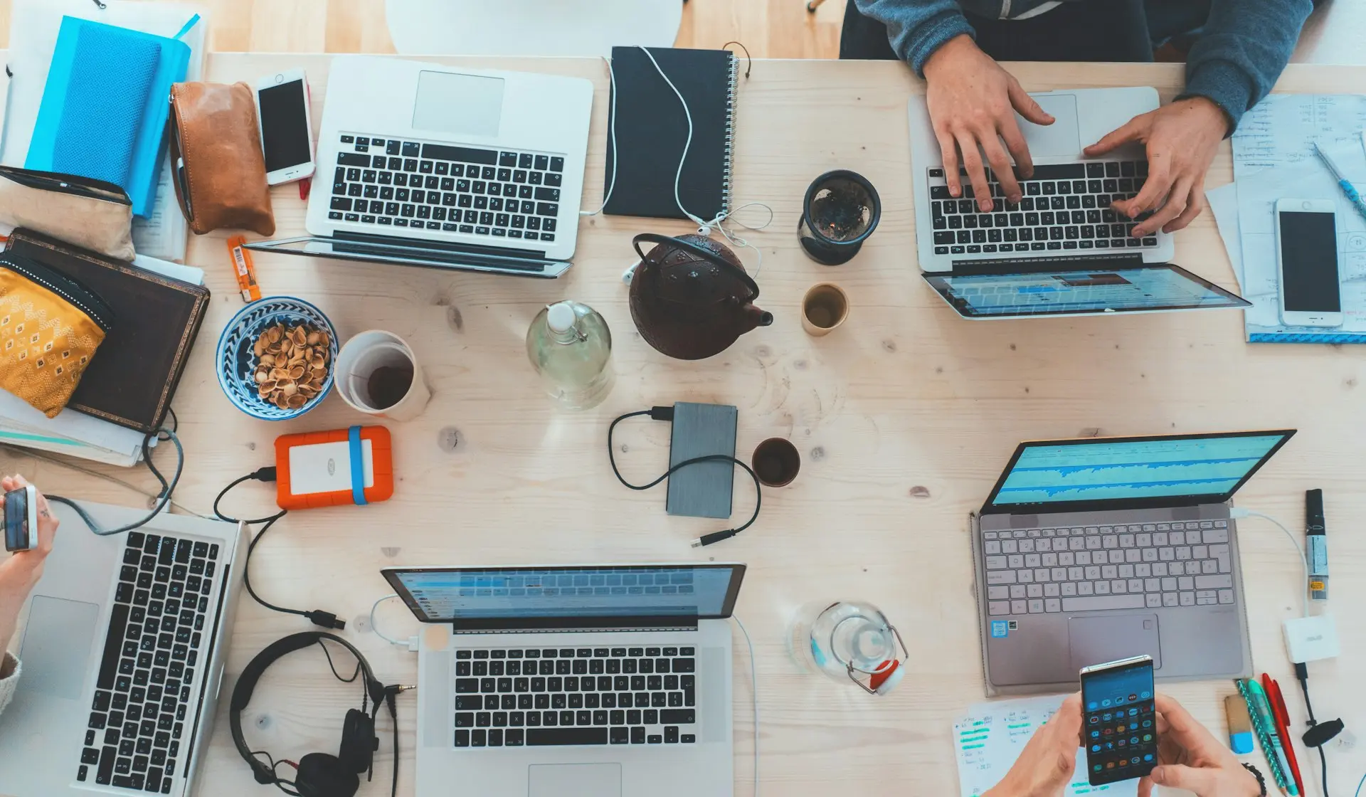 people sitting down near table with assorted laptop computers